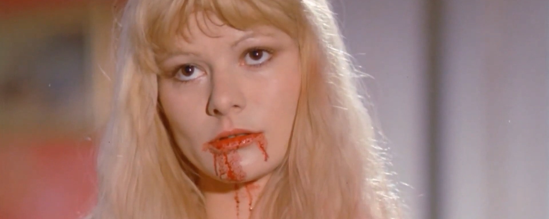 the living dead girl - a close-up of a woman whose mouth has blood on it.